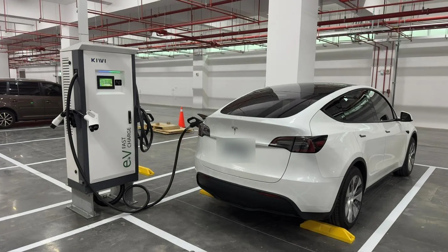 地下停車場的 60 kW 直流快充樁正在為電動車充電（車牌已模糊）