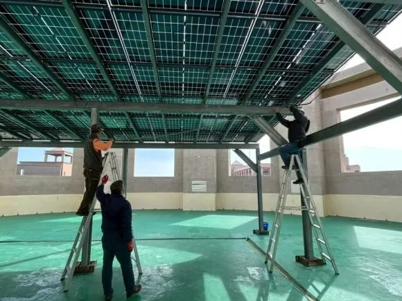 校園頂樓太陽能棚架施工，工程人員在梯子上安裝模組